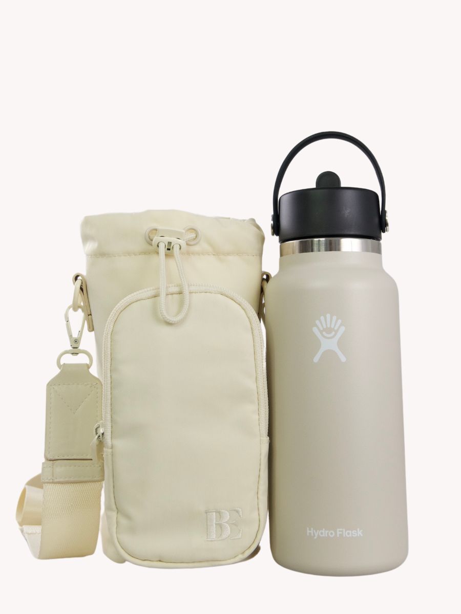 Beige antitheft water bottle bag next to a 1L Beige Hydro flask water bottle. Bag can most bottles up to 1L